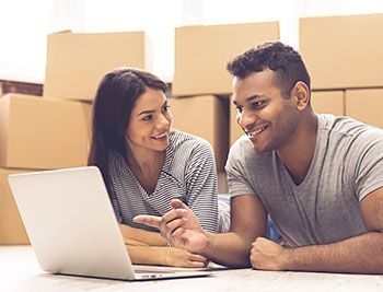 Couple using laptop to look at moving house quotes