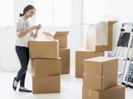 Young woman using packing supplies to pack her belongings