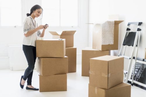 Young woman using packing supplies to pack her belongings