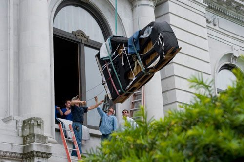 Crane carrying a piano - piano removals